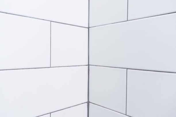 White rectangular subway tiles on two walls meeting at a corner with dark grout lines.