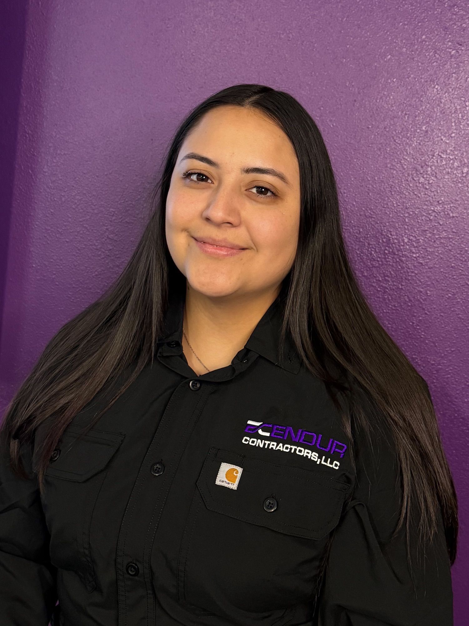 Portrait of a smiling person in a black shirt against a purple wall