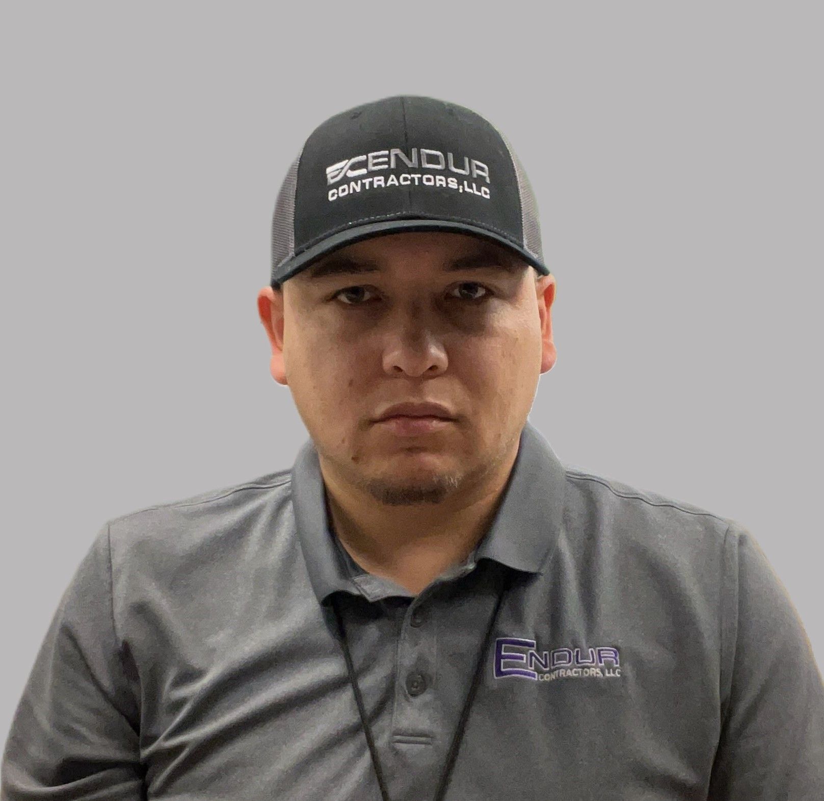 Man wearing a hat and polo shirt with a logo, looking forward.
