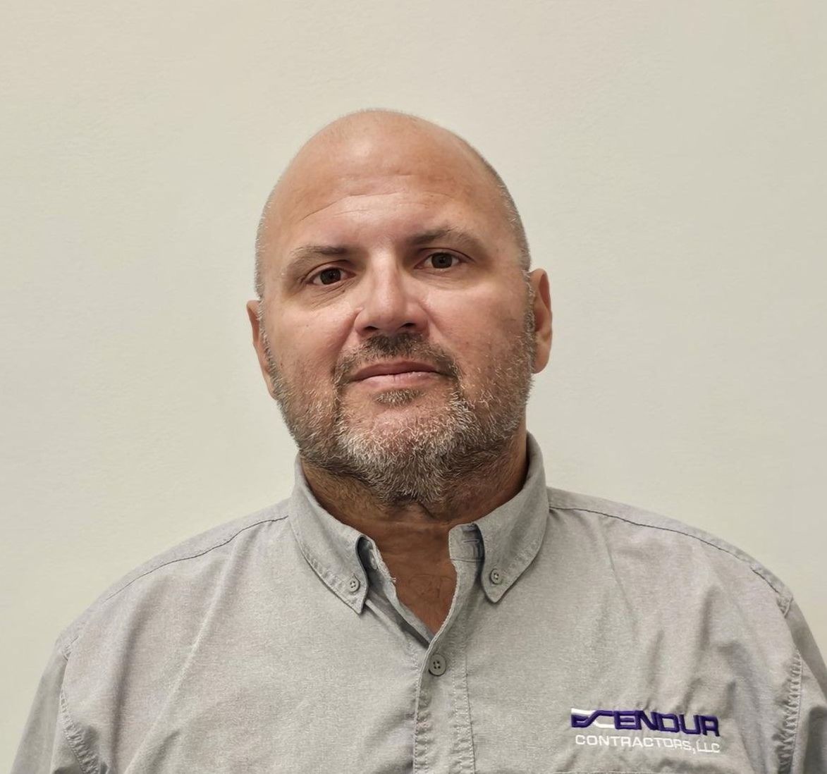 Man with shaved head and gray beard wearing a collared shirt.