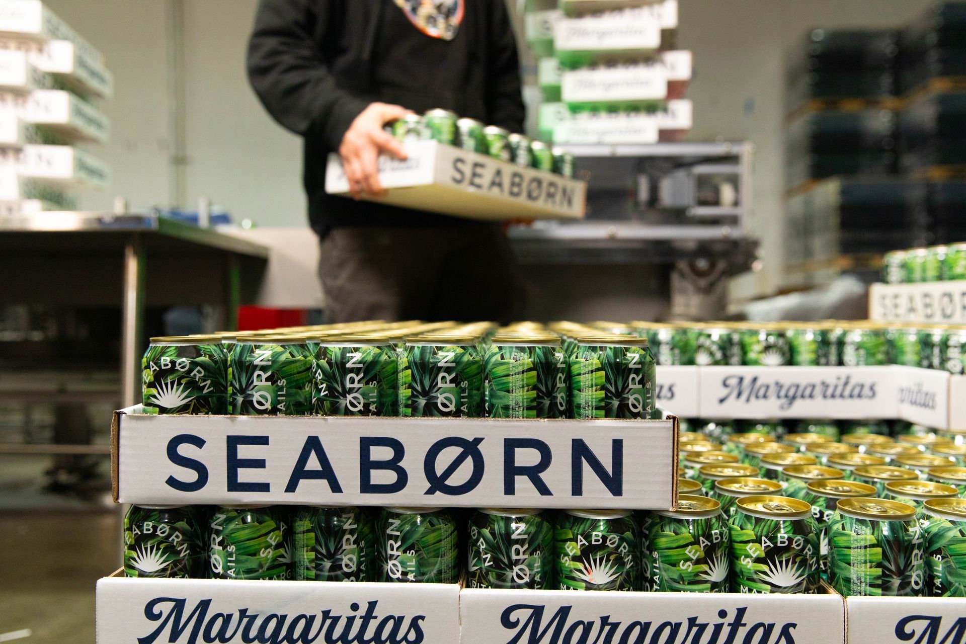 a man is working in a warehouse filled with lots of cans and bottles .