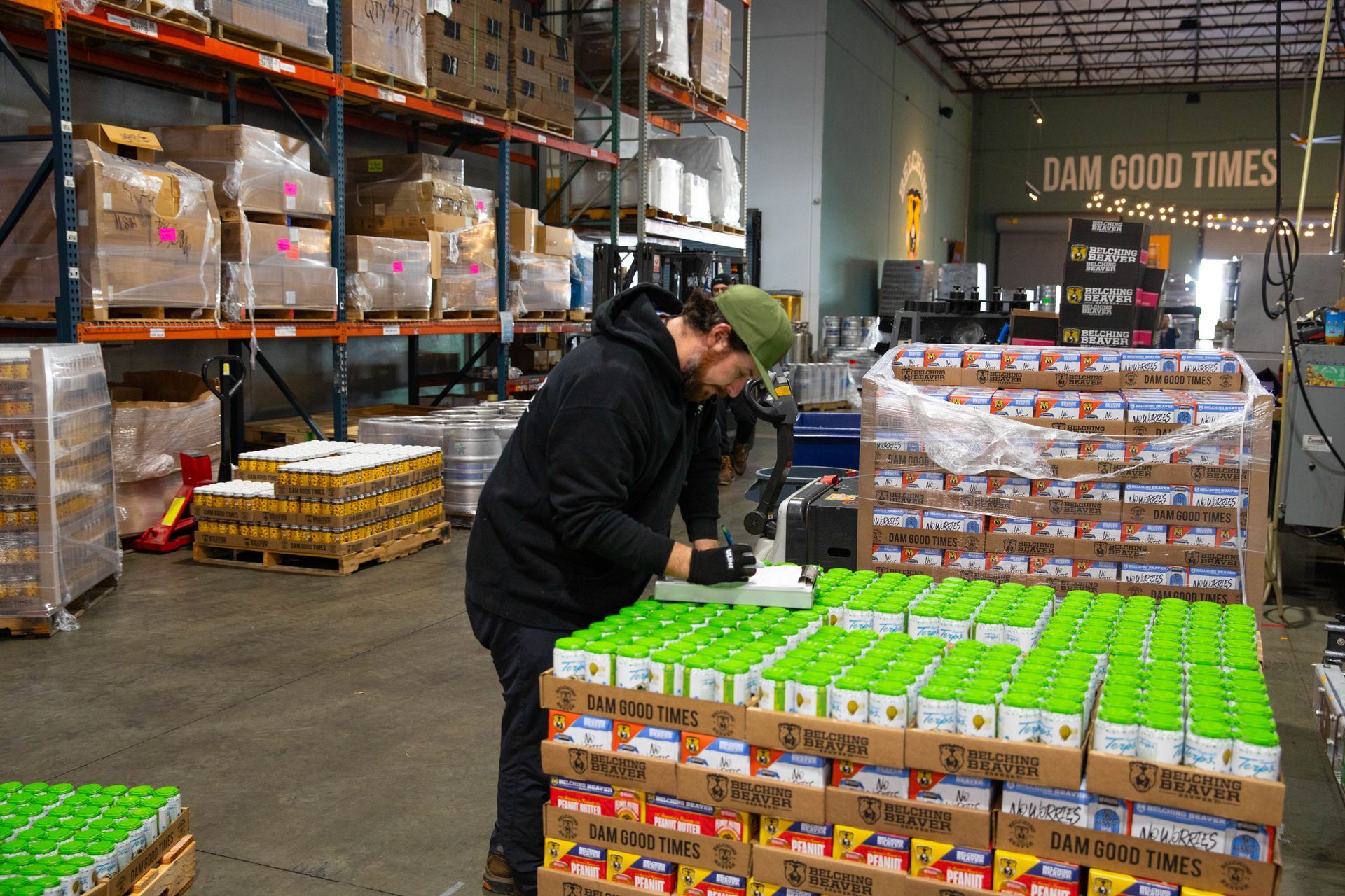 a man is working in a warehouse filled with lots of cans and bottles .