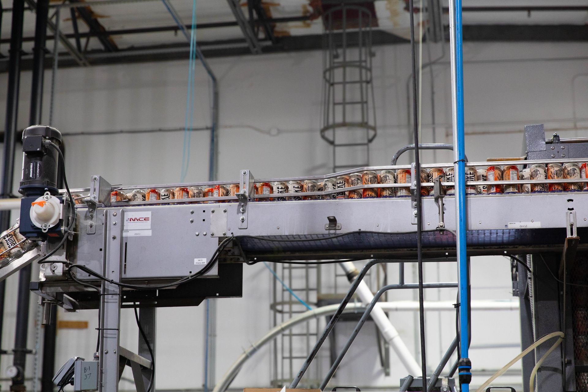 a conveyor belt filled with cans is in a factory.