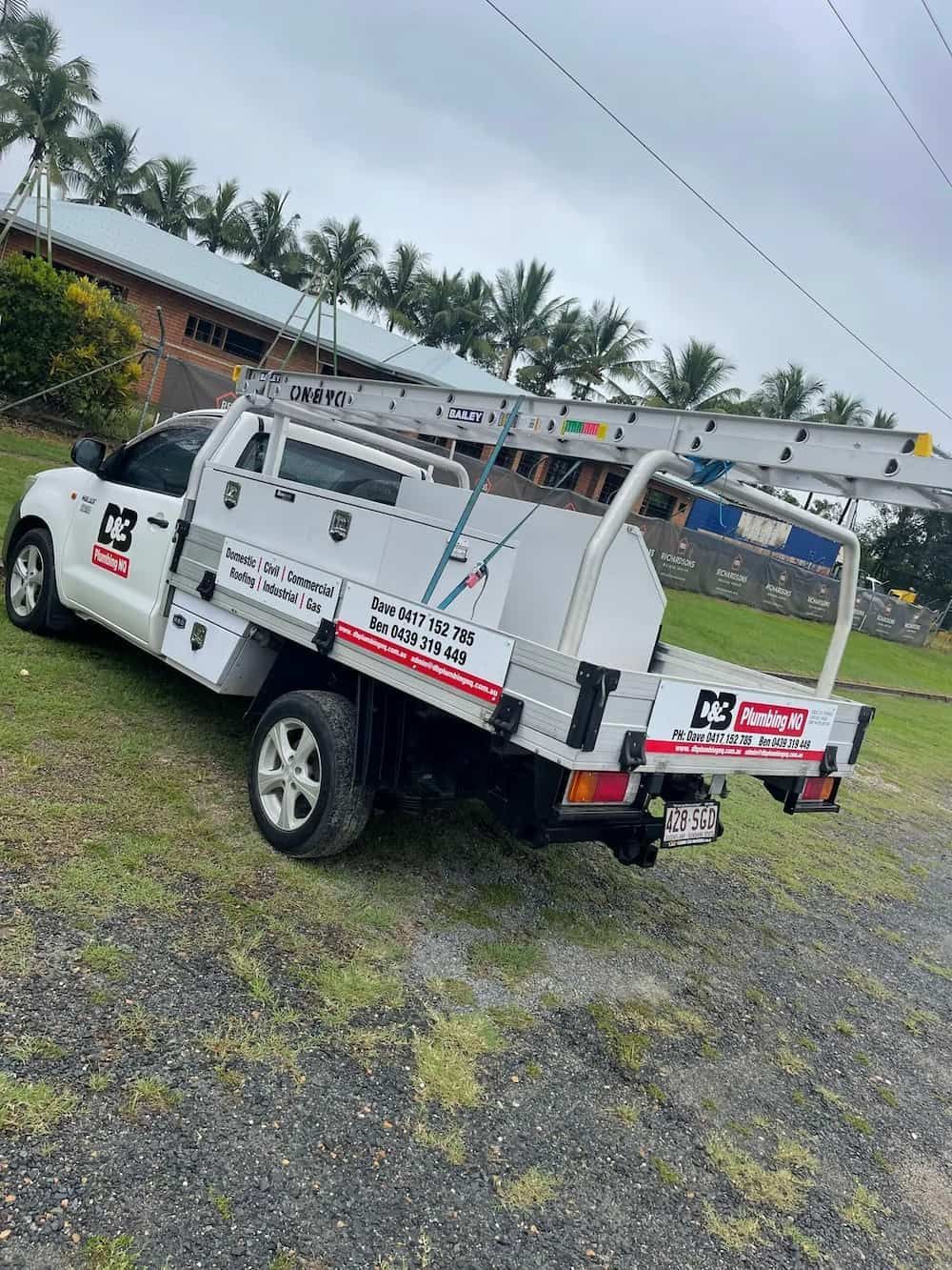 White Work Truck Parked on a Grassy Slope, With a Ladder on Top — D & B Plumbing NQ in Trinity Beach, QLD