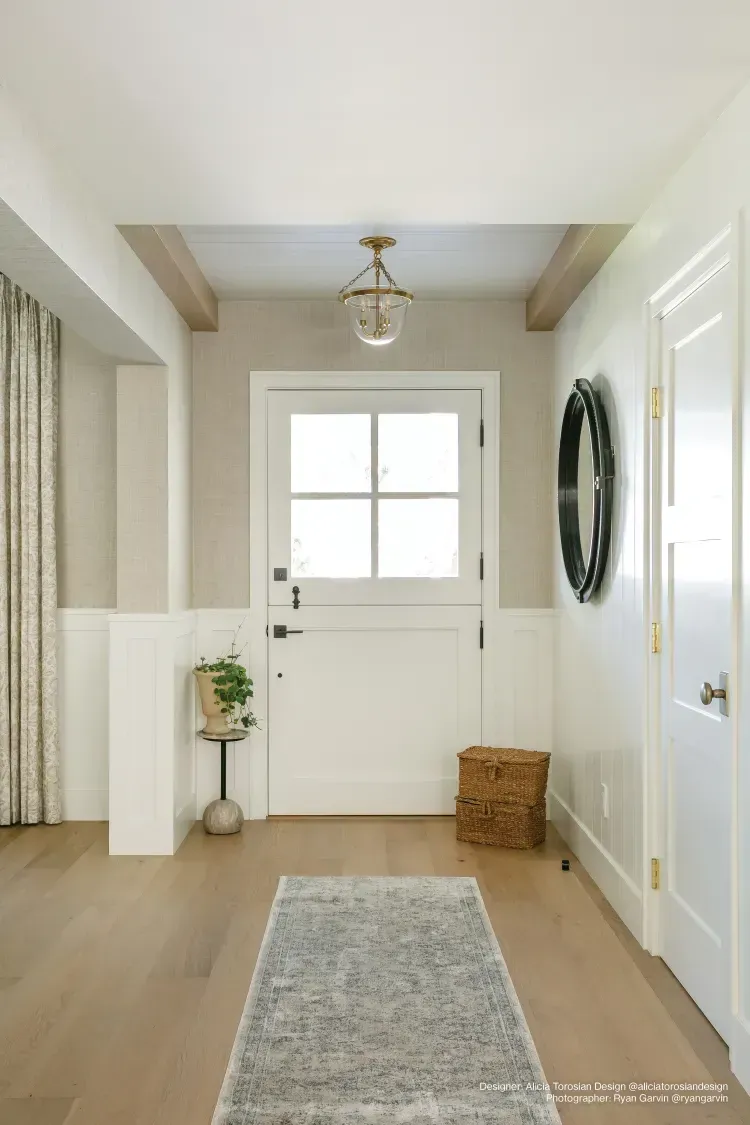 A hallway with a white door and a rug.