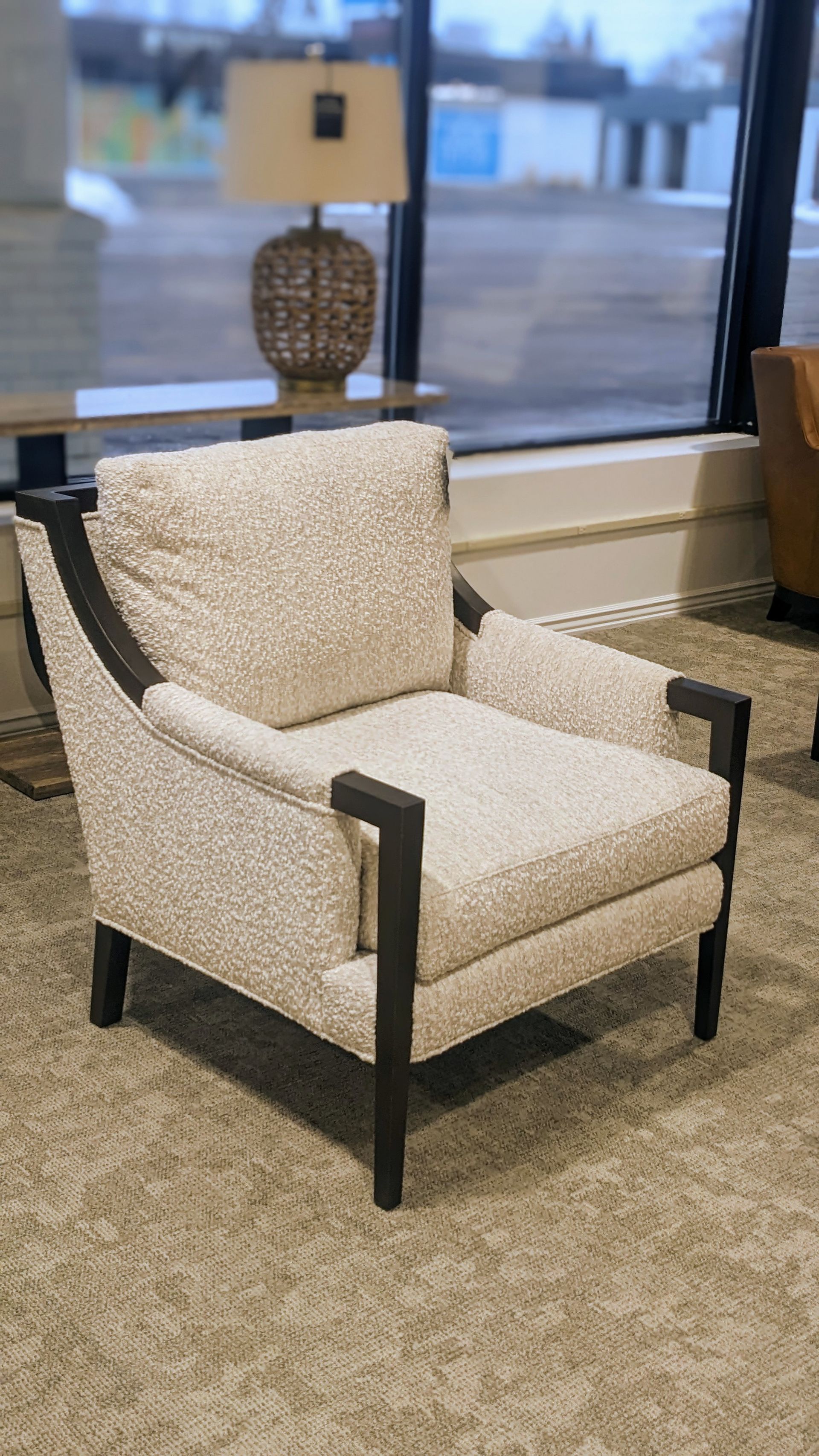 A white chair is sitting in a living room next to a window.