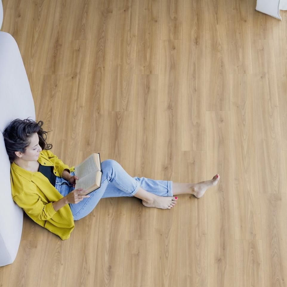 A woman is laying on the floor reading a book.