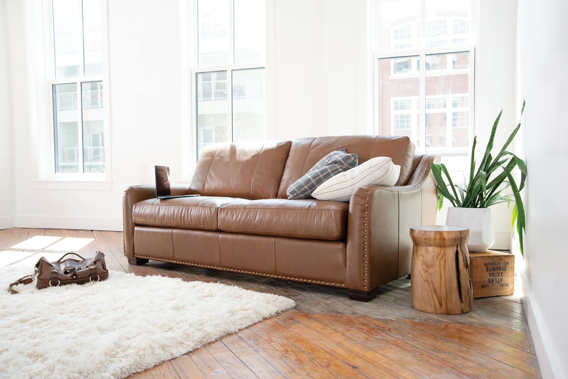 A living room with a brown leather couch and a white rug.