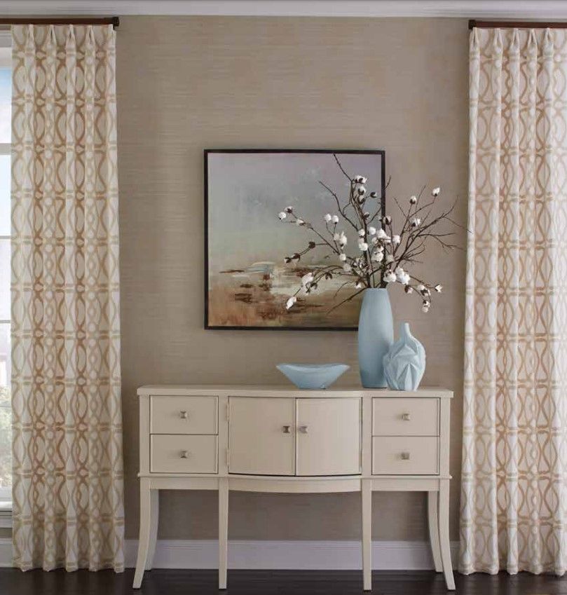 A table with a vase of flowers on it and a painting on the wall above it