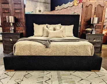 A bed with a black headboard and pillows on it