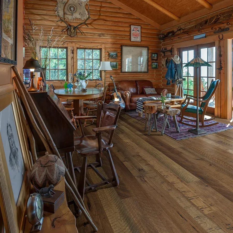 A living room in a log cabin with a couch and chairs