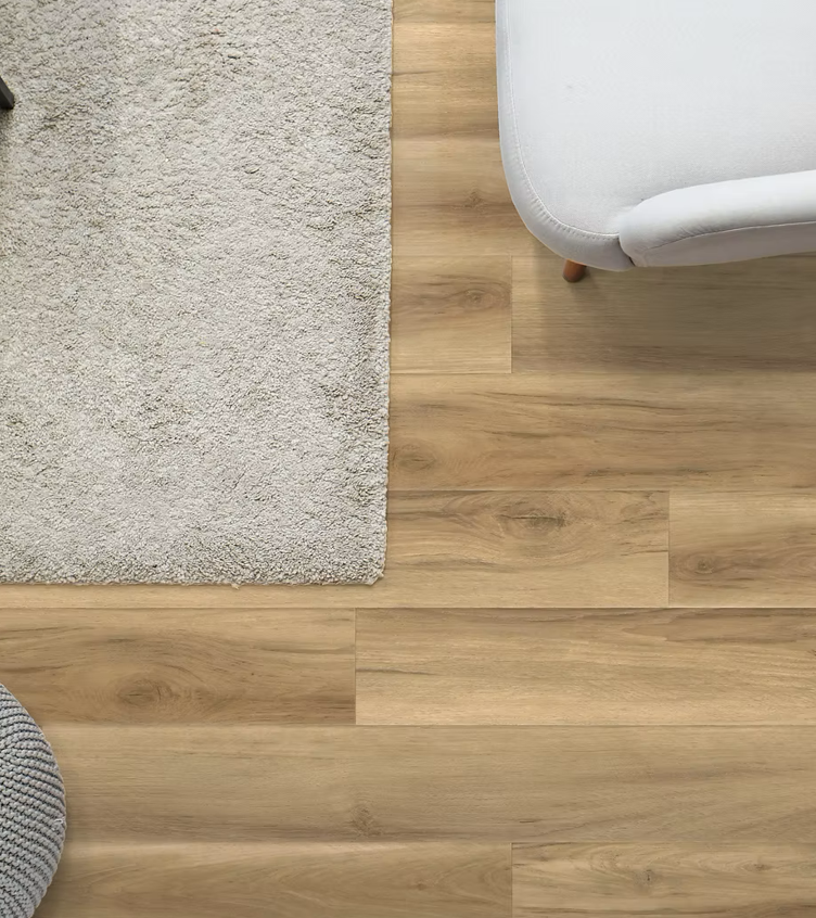 A living room with hardwood floors , a rug , a couch , and a chair.