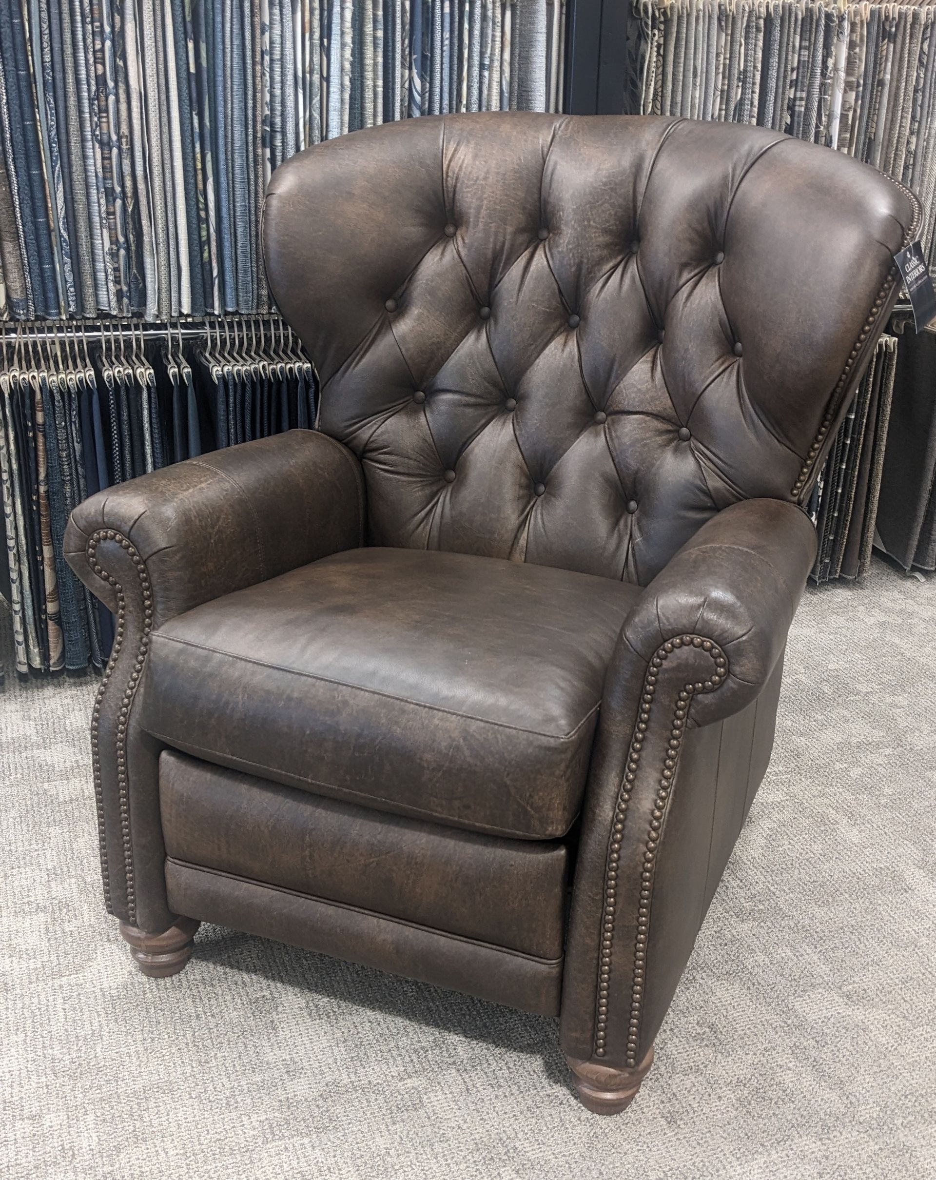 A brown leather recliner is sitting on a carpeted floor.