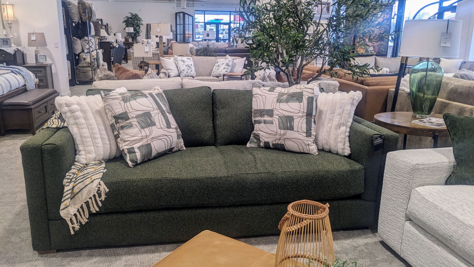A living room with a green couch and white pillows.