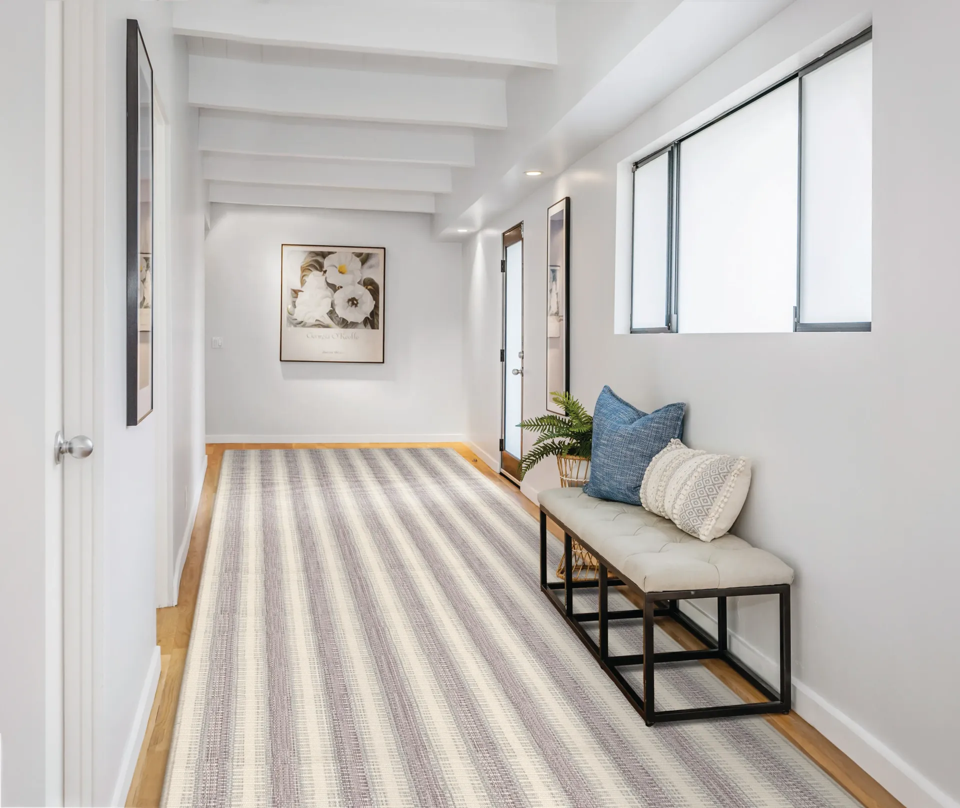 A hallway with a striped rug and a bench.