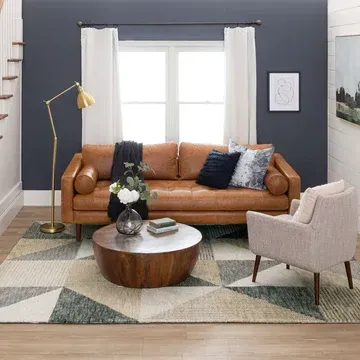 A living room with a couch , chair , coffee table and rug.