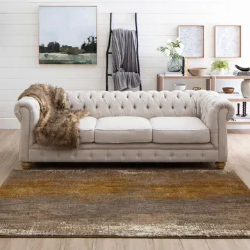 A white couch is sitting on top of a rug in a living room.