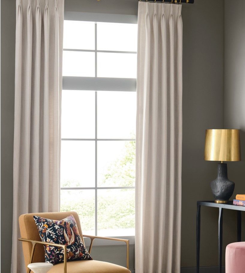 A living room with a chair , table , lamp and window.