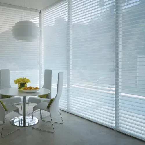 A dining room with a table and chairs and blinds on the windows