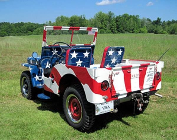 A red white and blue jeep is parked in a grassy field