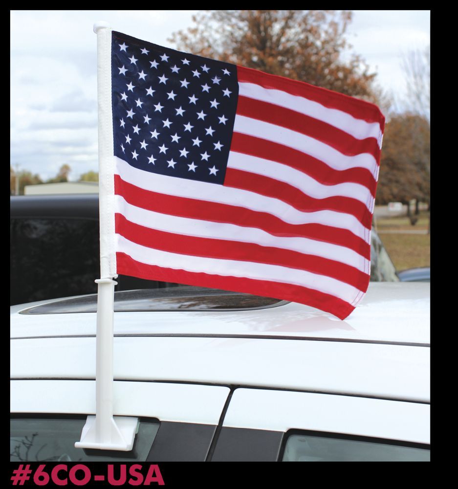 A small american flag on top of a white car