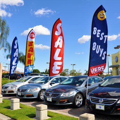 A lot of cars are parked in front of a car dealership
