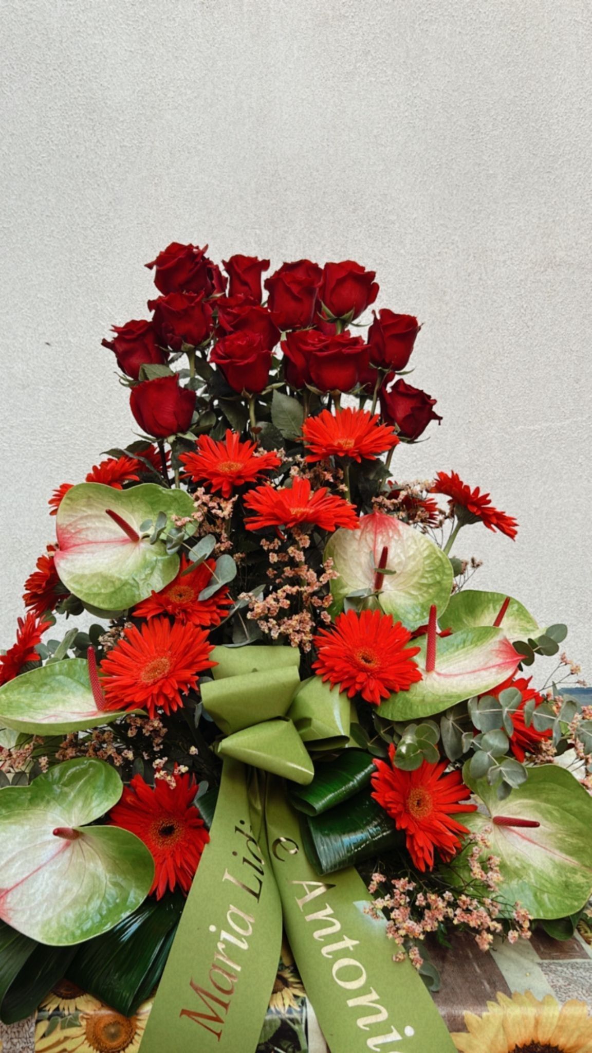 Composizione di rose rosse e crisantemi con anthurium verdi e nastro.