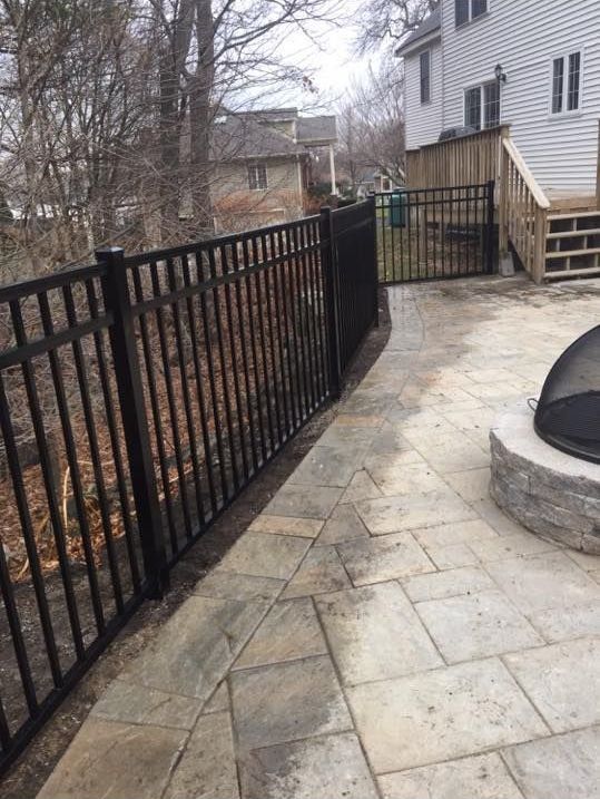 a black metal fence surrounds a patio with a fire pit .