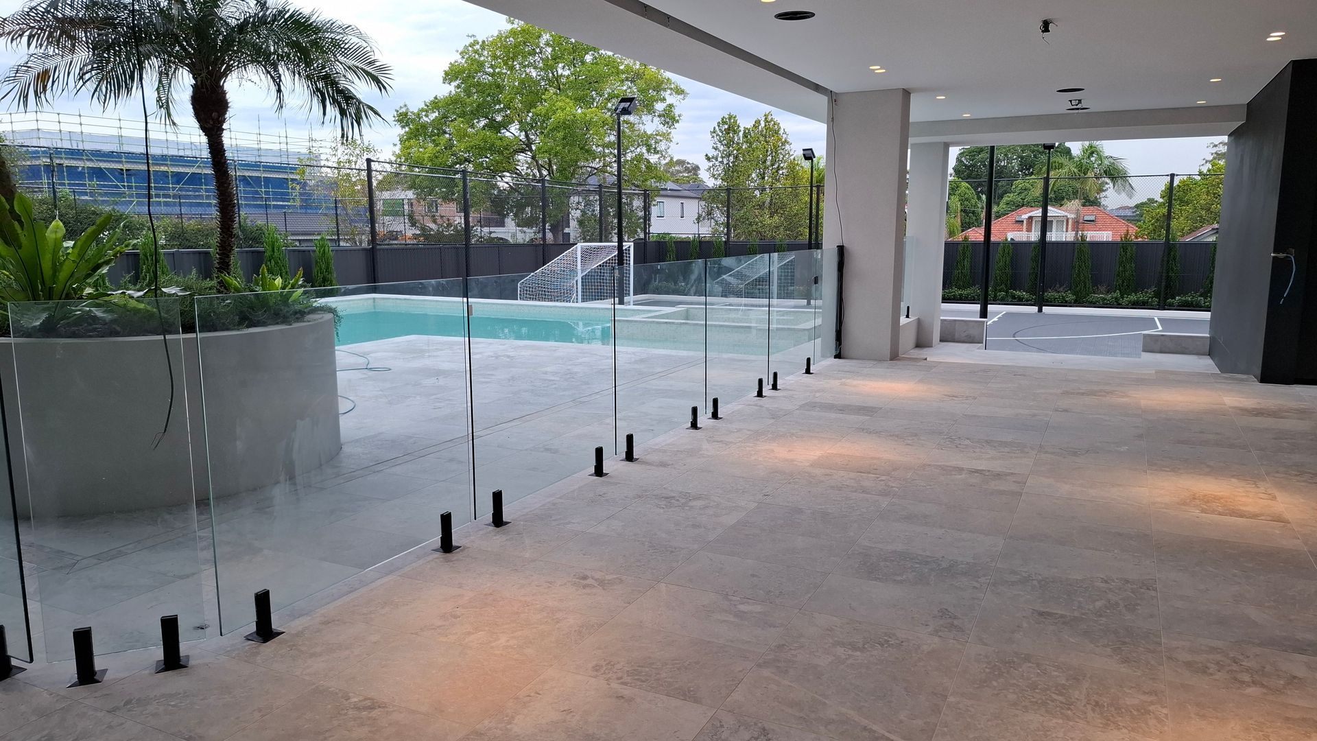 Pool area with glass barriers, palm tree, and concrete flooring - Sydney, NSW - Alta Trading Pty Ltd Pool area with glass barriers, palm tree, and concrete flooring - Sydney, NSW - Alta Trading Pty Ltd