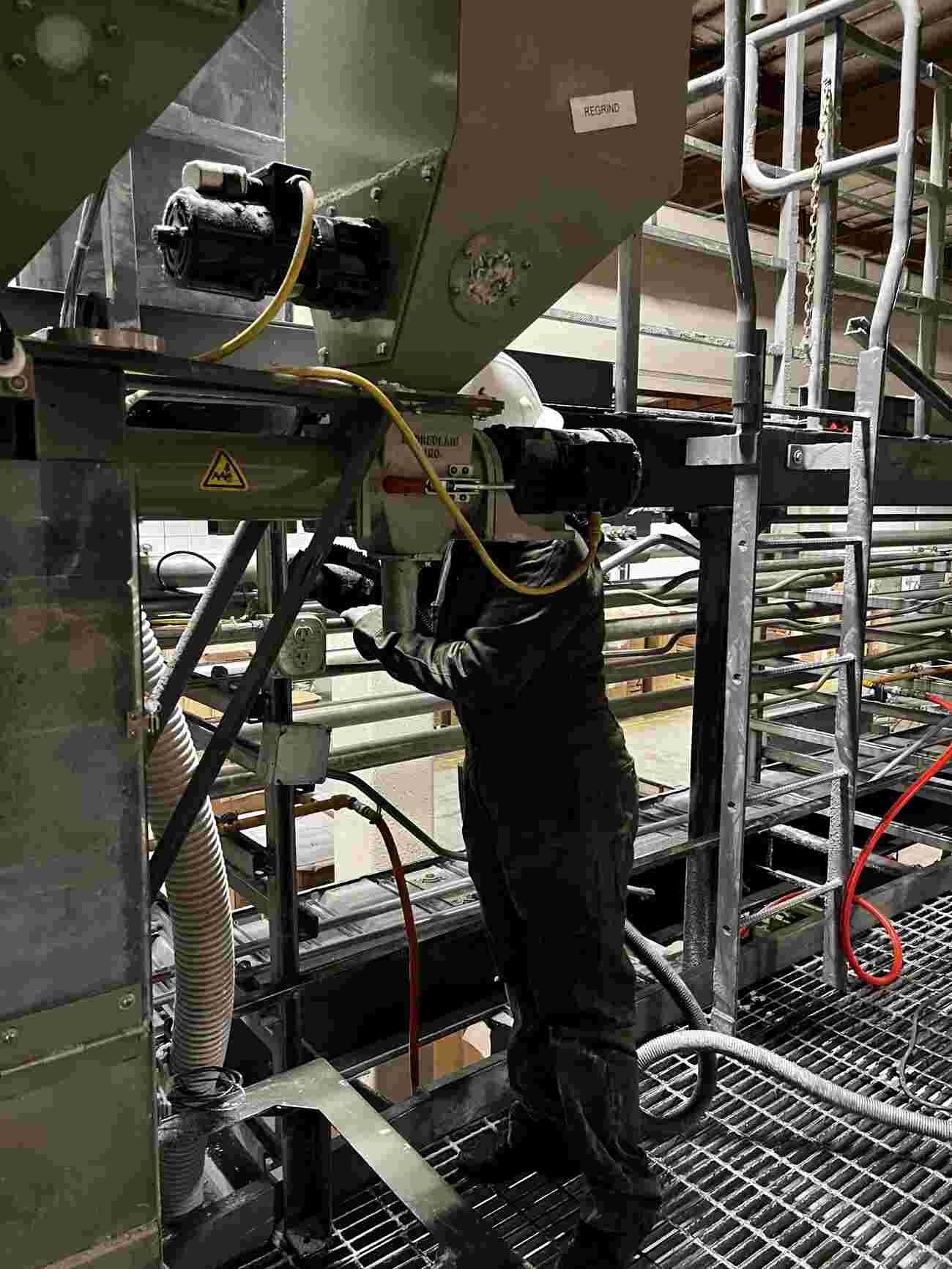 Cleaner cleaning a machine in a factory.