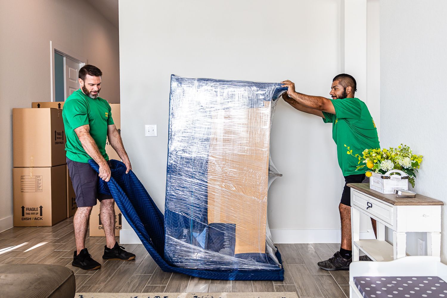 Two men are moving a large piece of furniture in a living room.