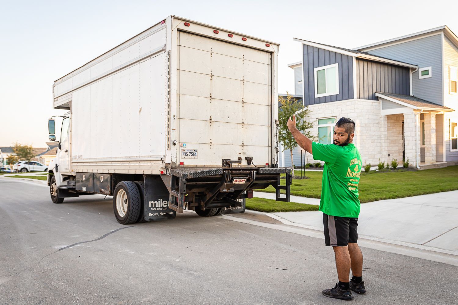 A man in a green shirt is standing in front of a moving truck.