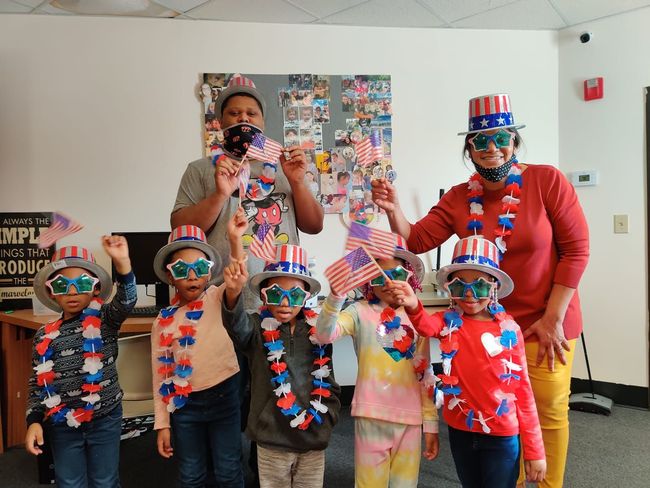 A group of people wearing patriotic hats and sunglasses are posing for a picture.