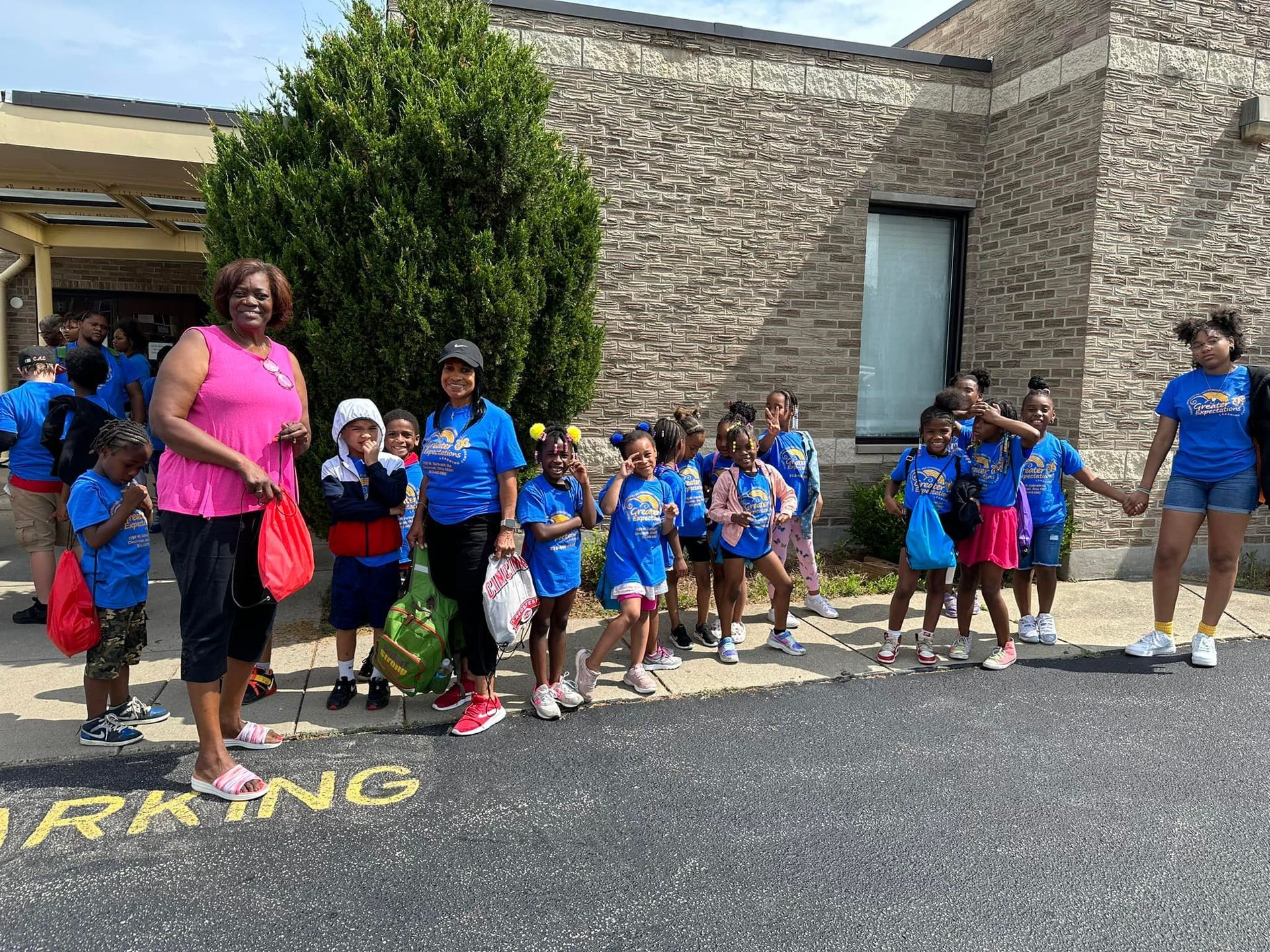 A group of children are standing in front of a building holding hands.