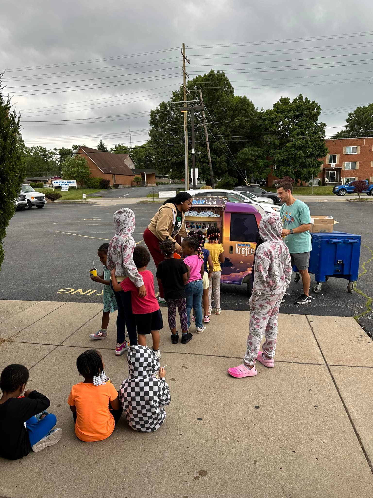 A group of children are standing in a parking lot.
