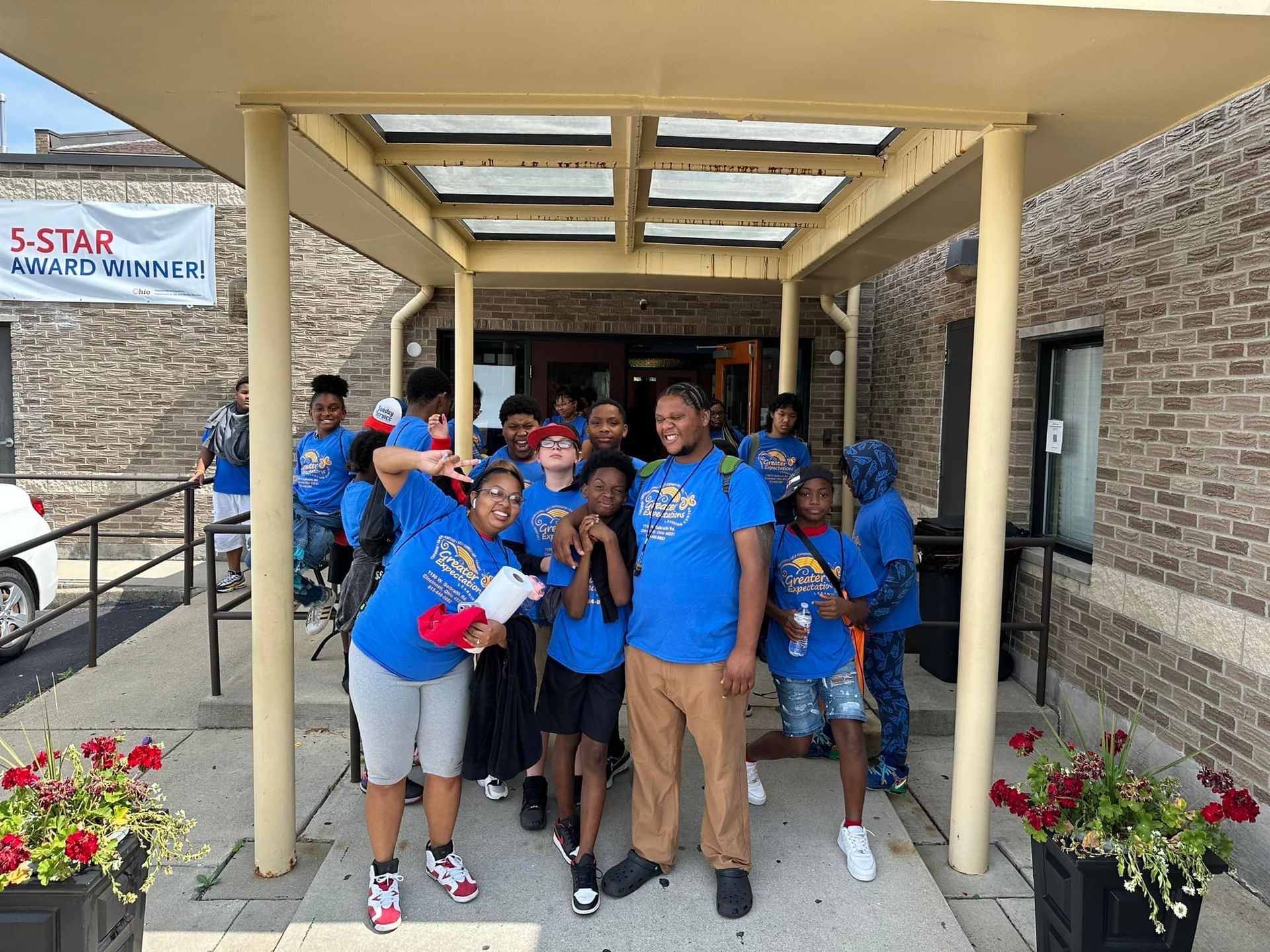 A group of people standing in front of a building wearing blue shirts.