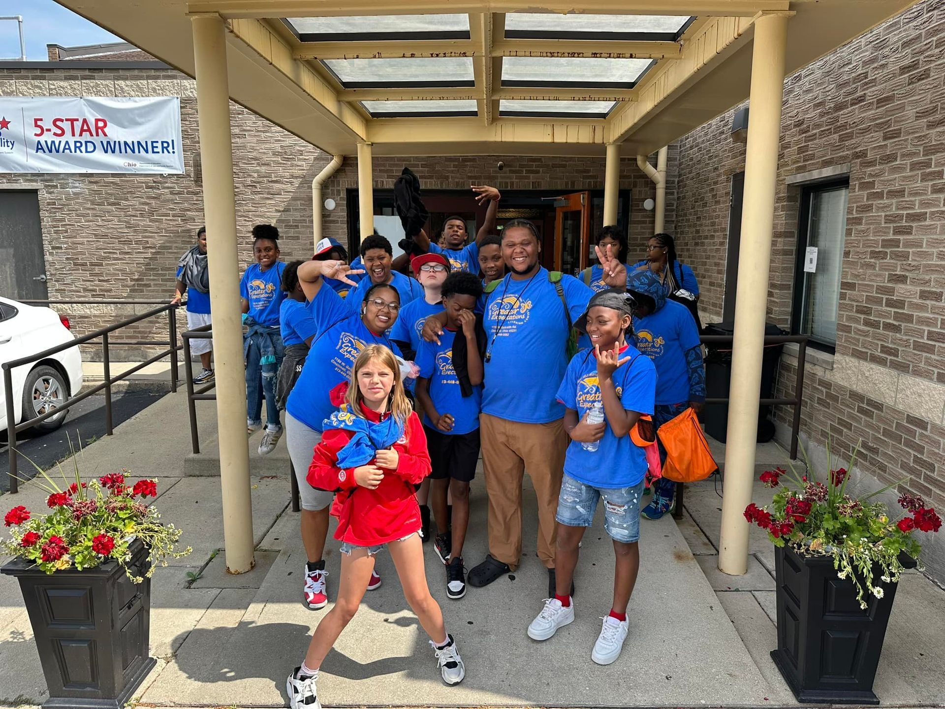 A group of young people are posing for a picture in front of a building.