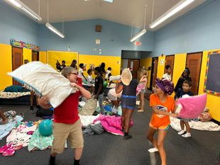 A group of children are playing with pillows in a room.