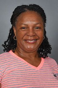 A woman wearing a pink striped shirt and earrings is smiling for the camera.