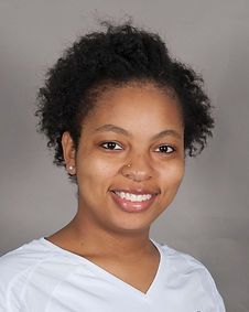 A woman with curly hair is smiling for the camera while wearing a white shirt.