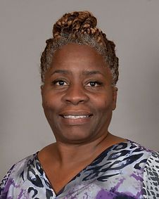 A woman in a purple shirt is smiling for the camera.