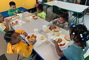 A group of children are sitting at a table eating food.