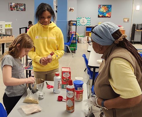 A group of people are standing around a table preparing food.