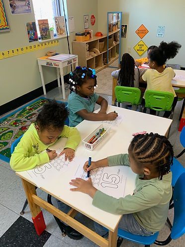 A group of children are sitting at a table in a classroom.