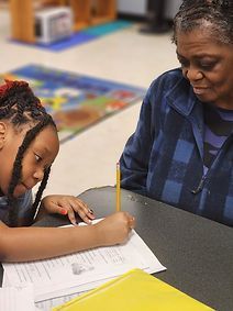 A woman is helping a young girl with her homework.