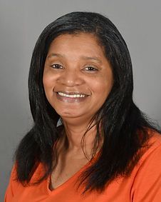 A woman with long black hair is smiling and wearing an orange shirt.