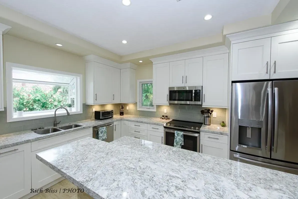House kitchen with white cabinets, granite counter tops, stainless steel appliances and a large island.