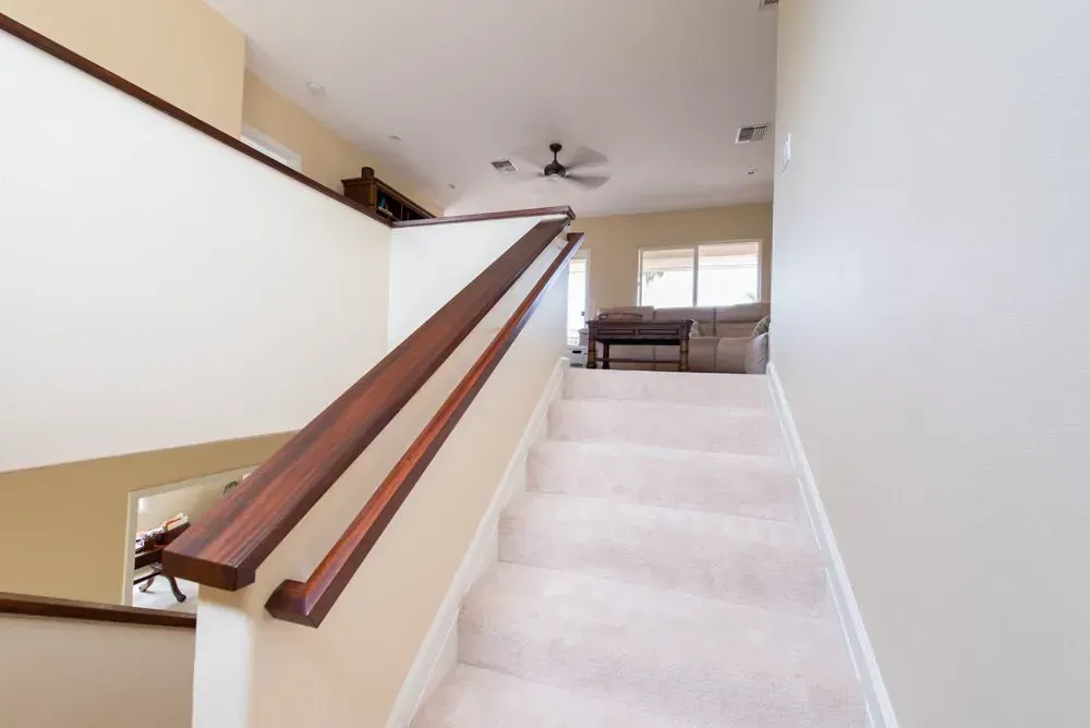 A staircase with a wooden railing leading up to a living room.