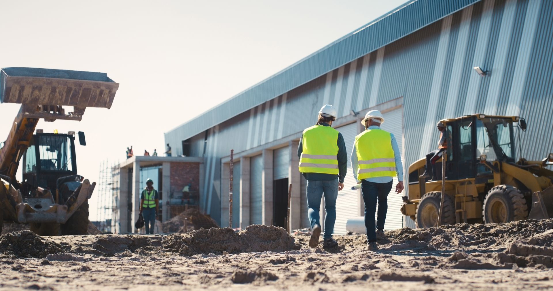 Professionals from a commercial construction company with materials and equipment in the background.
