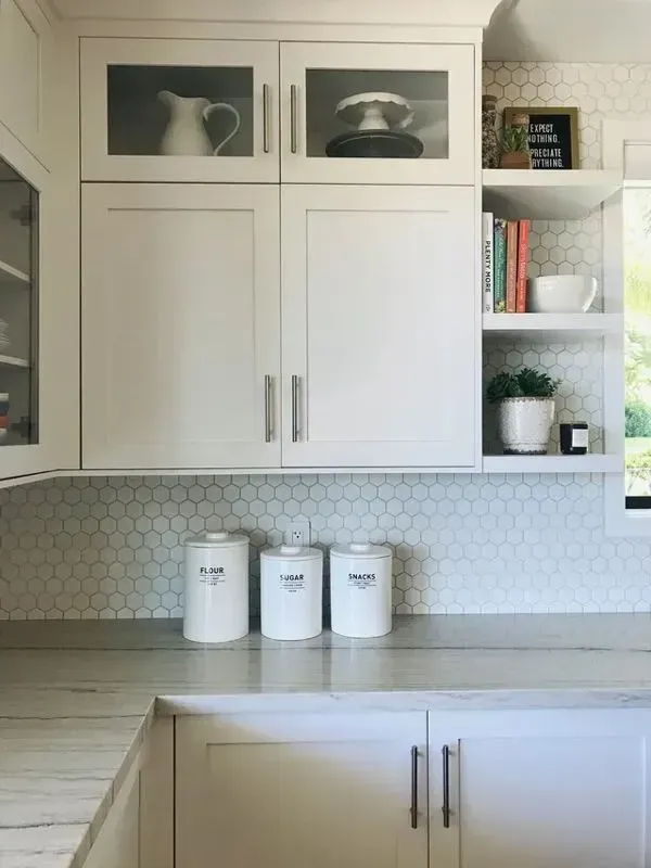 A kitchen with white cabinets , counter tops , and shelves.
